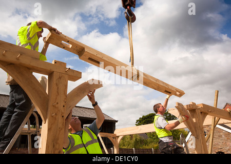 self building house, constructing green oak timber framed structure, using hired crane to lift heavy wooden frame Stock Photo