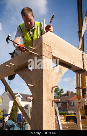 self building house, constructing green oak timber framed garage, pegging frame, whist crane lifts heavy structure Stock Photo