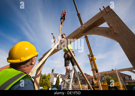 self building house, constructing green oak timber framed structure, using hired crane to lift heavy wooden frame Stock Photo