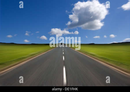 Rural road stretching out into the distance with motion blur under a big expanse of blue sky.