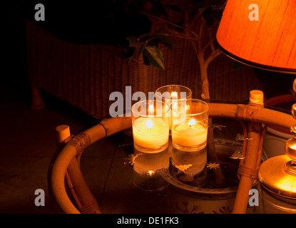 Three candles in glass holders on glass table at Christmas. Night shot. Stock Photo
