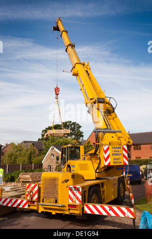 self building house, constructing green oak timber framed structure, using hired crane to lift heavy wooden components Stock Photo