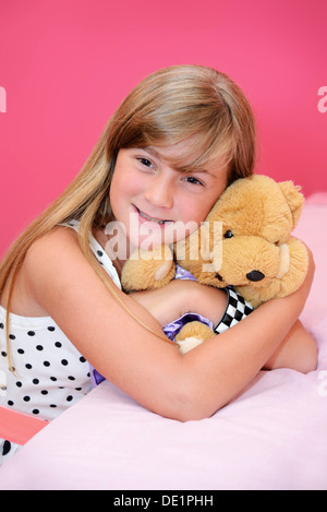 pretty little blonde girl on pink background with smile and teddy bear Stock Photo