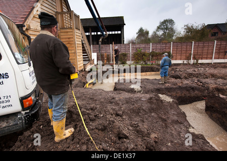 self building house, concrete foundations being poured and tamped level Stock Photo