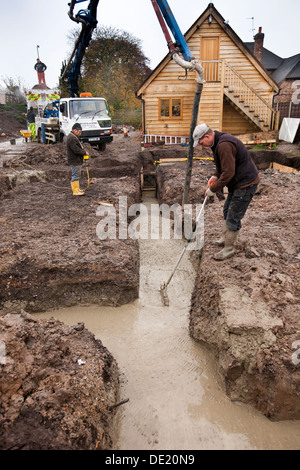 self building house, concrete foundations being poured and tamped level Stock Photo