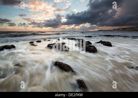 Waves breaking onto a Rocky Beach during sunset Stock Photo