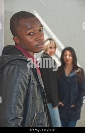 Dark-skinned young man and two young women talking to each other Stock Photo