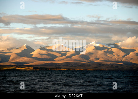 Dark waters of Lake Manasarovar, a sacred lake in front of the Gurla Mandhata mountain range with shadows, Himalayas Stock Photo