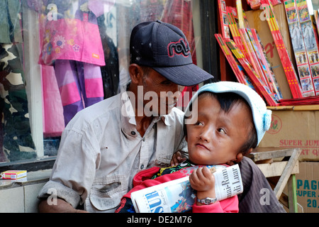 local man begging on the streets of malang with his young son who suffers from hydrocephalus java indonesia Stock Photo