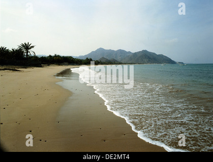 A sandy beach in Fujairah emirate, with mountains in the background.