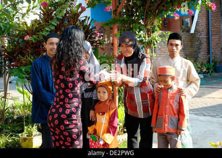 local woman greeting her neighbours who are visiting traditional during the idul fitri holidays Stock Photo