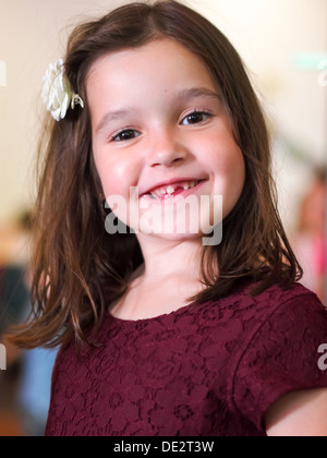 A young girl smiling with a front tooth missing Stock Photo