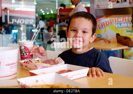 happy little boy of mixed race enjoying a chicken meal at kfc in malang java indonesia Stock Photo