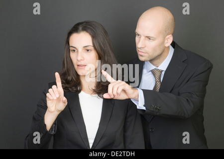 Virtual screen, businessman and businesswoman pressing their fingers on a virtual screen Stock Photo