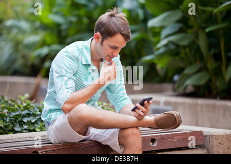 Man sitting in garden using a smart phone Stock Photo
