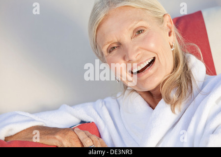 Happy senior woman sitting smiling in spa bathrobe Stock Photo