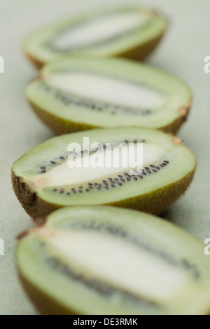 Juicy and appetizing fresh kiwi fruit cut in half and laid out in a row on a wooden surface Stock Photo