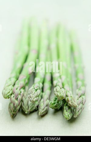 A bunch of fresh green delicious and appetizing asparagus laid down on a textured wooden surface with minimal focus Stock Photo