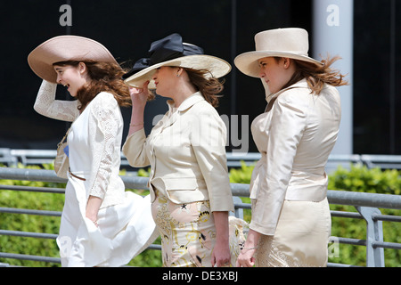 Ascot, UK, elegantly dressed women hold in high winds Huete their fixed Stock Photo