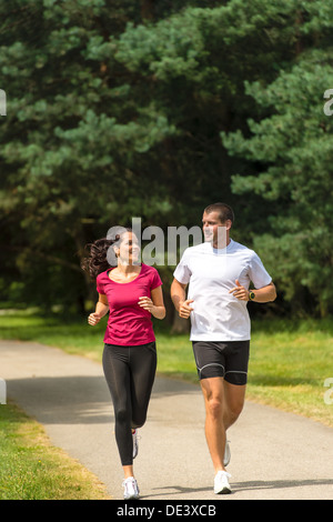 Smiling young couple running in park Stock Photo