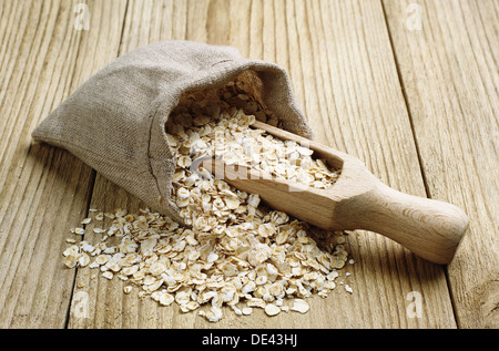 Oat flake in a sack and spoon on the wooden table Stock Photo