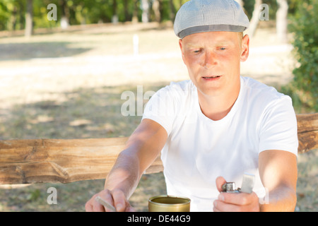 Middle-aged man about to light a cigarette concentrating on flicking his lighter to get a flame Stock Photo