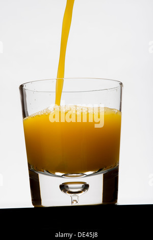 Freshly squeezed pure and healthy orange juice being poured into a glass for breakfast Stock Photo