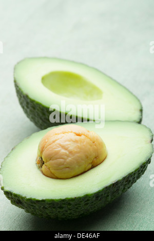 Delicious, fresh, juicy and appetizing avocado fruit cut in half and laid out on a wooden surface Stock Photo