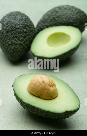 Delicious, fresh, juicy and appetizing avocado fruit cut in half and laid out on a wooden surface Stock Photo