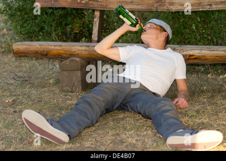 Alcoholic passed out on the ground in a park lying with his head Stock ...