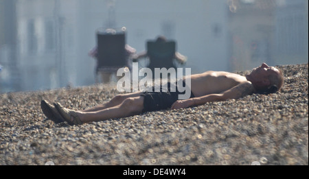 man asleep on shingle beach Stock Photo