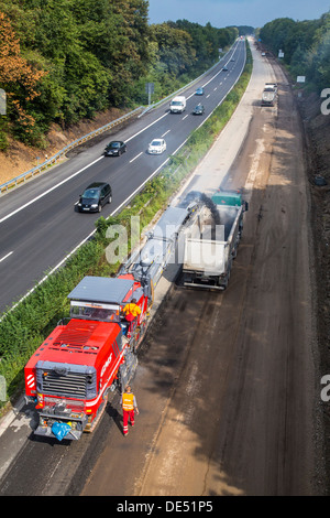 Roadworks, on Autobahn A52, Essen, Germany.  Removal of the asphalt surface with a cutter, then new, porous asphalt is applied.