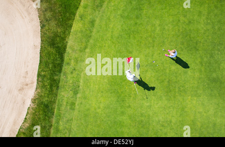Two golfers on a green, putting. Stock Photo