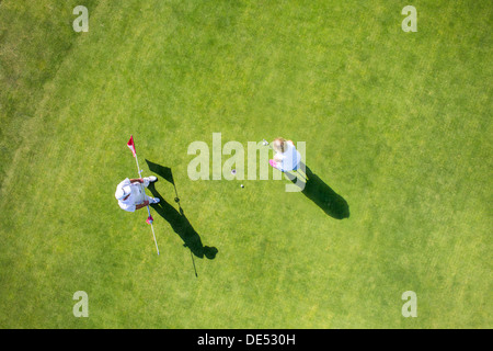 Two golfers on a green, putting. Stock Photo