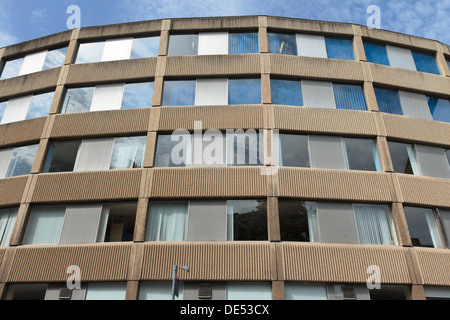 Windows reflecting sky in a 1960s curved reinforced concrete Brutalist office building with ribbed concrete panels in Bristol. Stock Photo
