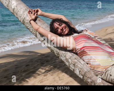 Woman, 45, relaxing by lying on a palm tree, Punta Uva, Puerto Viejo de Talamanca, Costa Rica, Central America Stock Photo