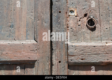 fragment of ancient weathered wooden door with rusty ring handle Stock Photo