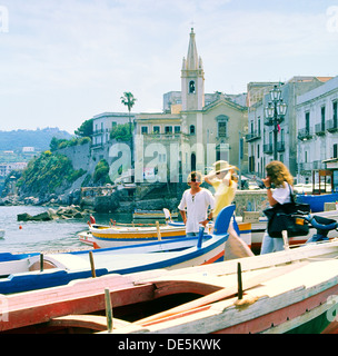 The Aeolian Island of Lipari, Italy. Young women visitors and local boatman in the Marina Corta in the town of Lipari. Stock Photo