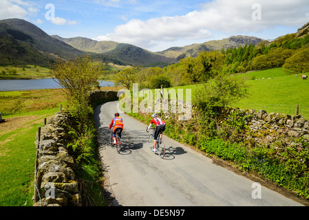 Cyclists in Little Langdale in the English Lake District with Little Langdale Tarn and the Coniston Fells behind Stock Photo