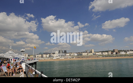 Tourists sunbathing on the Pier Brighton with Beach in the background East Sussex England Stock Photo
