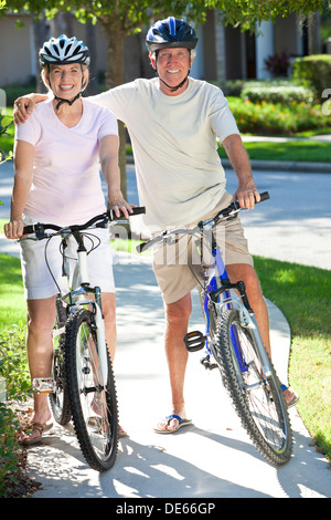 Happy senior man and woman couple together cycling on bicycles on a sunny summer day Stock Photo