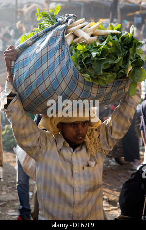 India, Uttar Pradesh, Agra, man carrying carrots in vegetable market Stock Photo