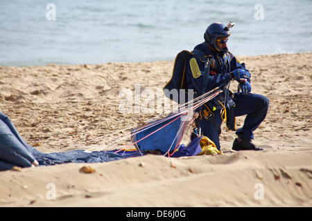 Parachutist looking at watch to see timing after his descent onto Bournemouth beach as part of Bournemouth Air Festival, Dorset UK in September Stock Photo