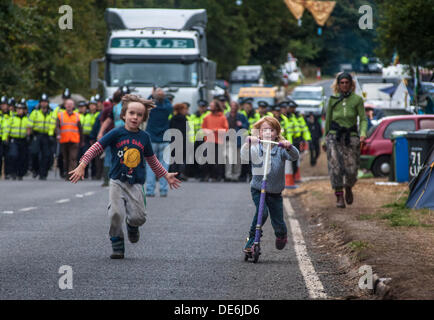 Balcombe,West Sussex, UK. 12th Sept, 2013.Children play as another lorry arrives to be escorted to Cuadrilla site by Police as protesters walk in front. The anti fracking environmentalists are protesting against test drilling by Cuadrilla on the site in West Sussex that could lead to the controversial fracking process. Credit:  David Burr/Alamy Live News Stock Photo
