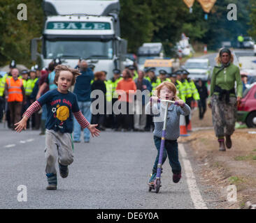 Balcombe,West Sussex, UK. 12th Sept, 2013. Children play as in the background a lorry is escorted to Cuadrilla site by Police as environmentalists walk in front... The anti fracking environmentalists are protesting against test drilling by Cuadrilla on the site in West Sussex that could lead to the controversial fracking process. Credit:  David Burr/Alamy Live News Stock Photo