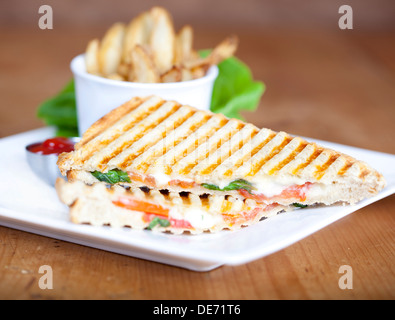 Grilled caprese sandwich with fried potatoes and ketchup on a plate Stock Photo