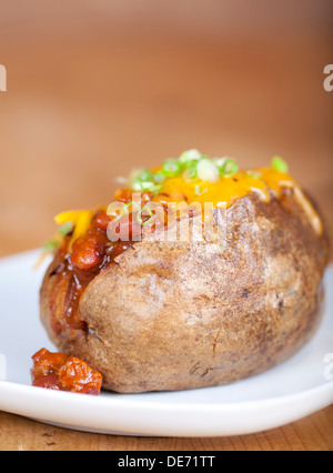 Loaded baked potato with chili and cheese on a plate Stock Photo