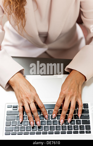 Female hands typing on laptop keyboard from above Stock Photo