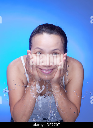 In a studio setting, a Korean woman splashes water on her face. Stock Photo