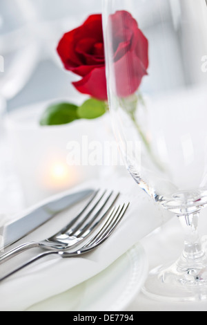 Romantic restaurant table setting with rose candle plates and cutlery Stock Photo